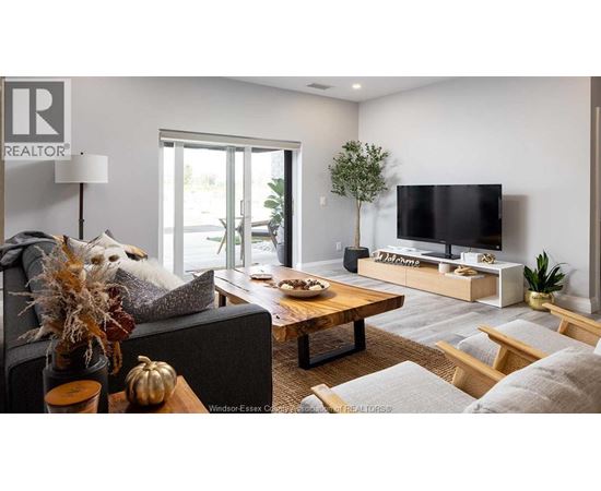 A living room with a grey couch, a wooden coffee table, a flat screen TV, and a plant.