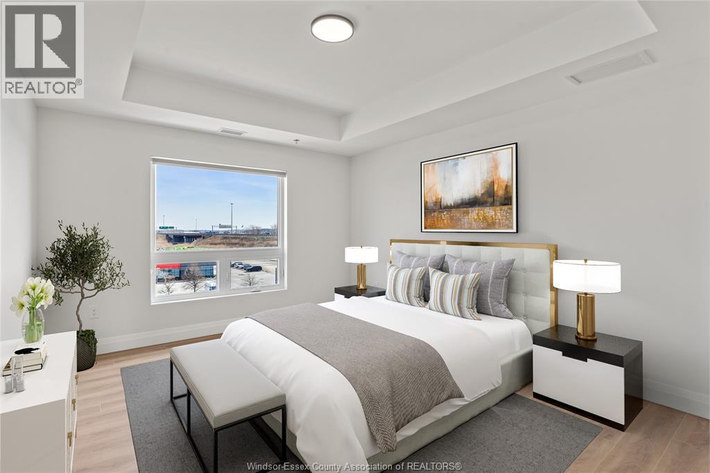 A bedroom with a large bed, a nightstand with a lamp, and a framed picture on the wall.