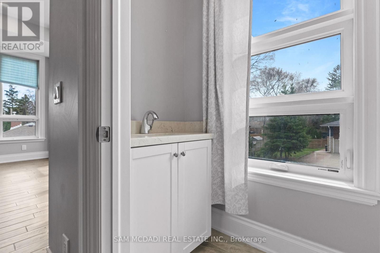 A bathroom with a window showing a view of trees and a road outside.