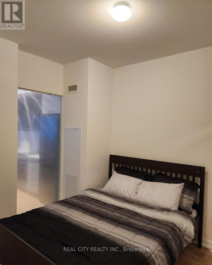 A bedroom with a bed, pillows, and a window with a view of a cityscape.