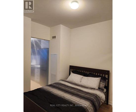 A bedroom with a bed, pillows, and a window with a view of a cityscape.