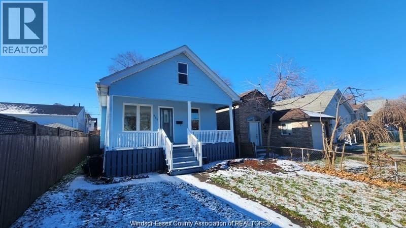 A blue house with a white fence in front of it.