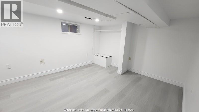A large empty room with a window and a white table in the corner.