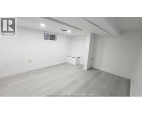 A large empty room with a window and a white table in the corner.
