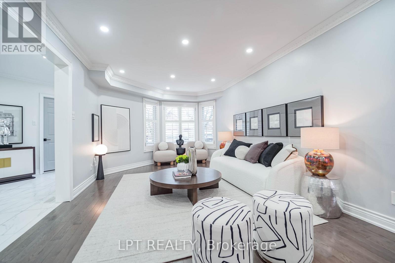 A well-lit, modern living room with a white sofa, a coffee table, and a large window.