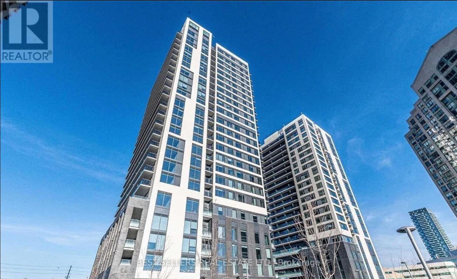 A tall building with many windows is under a blue sky.