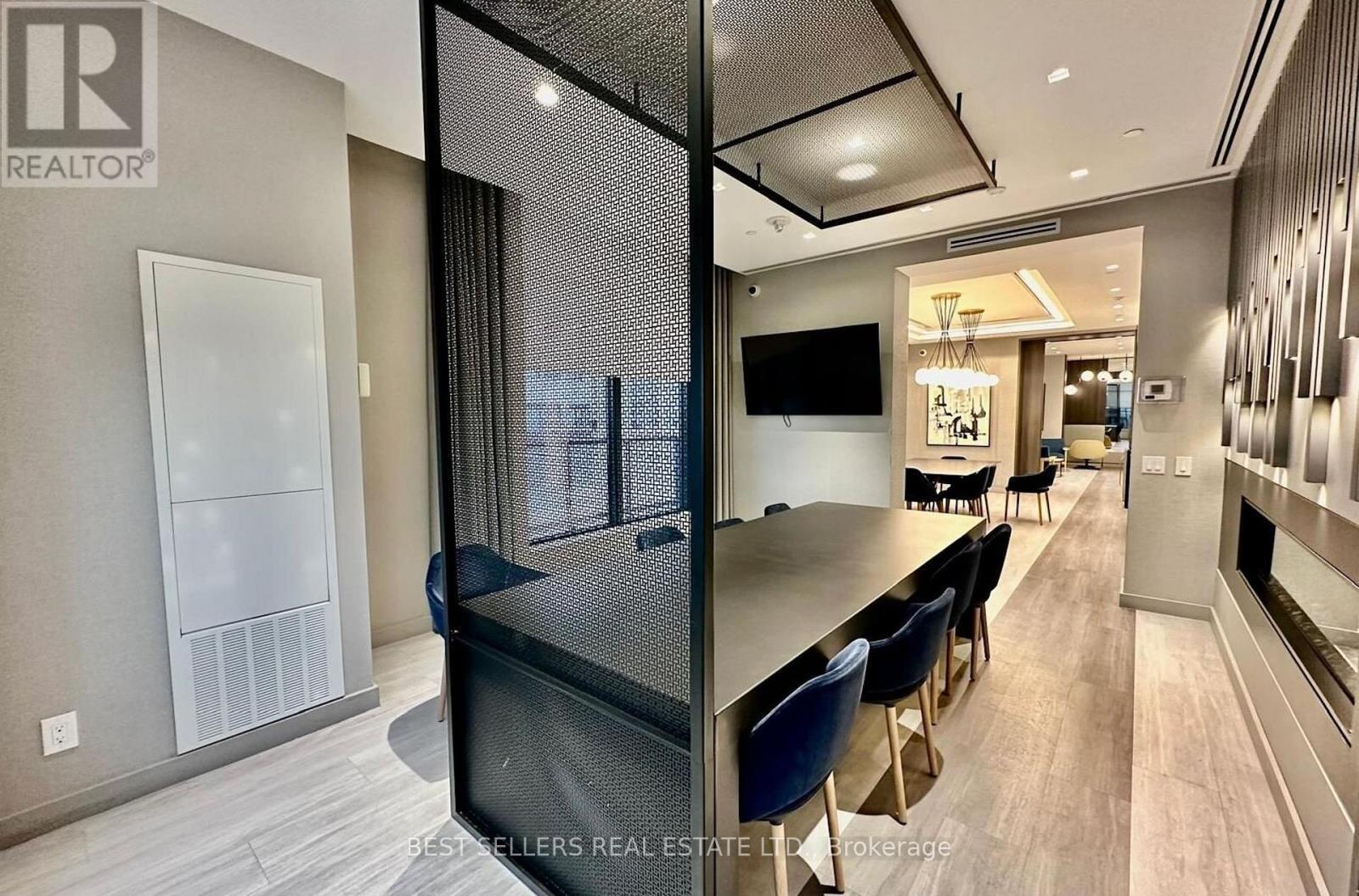A modern dining area with a glass partition and a television mounted on the wall.