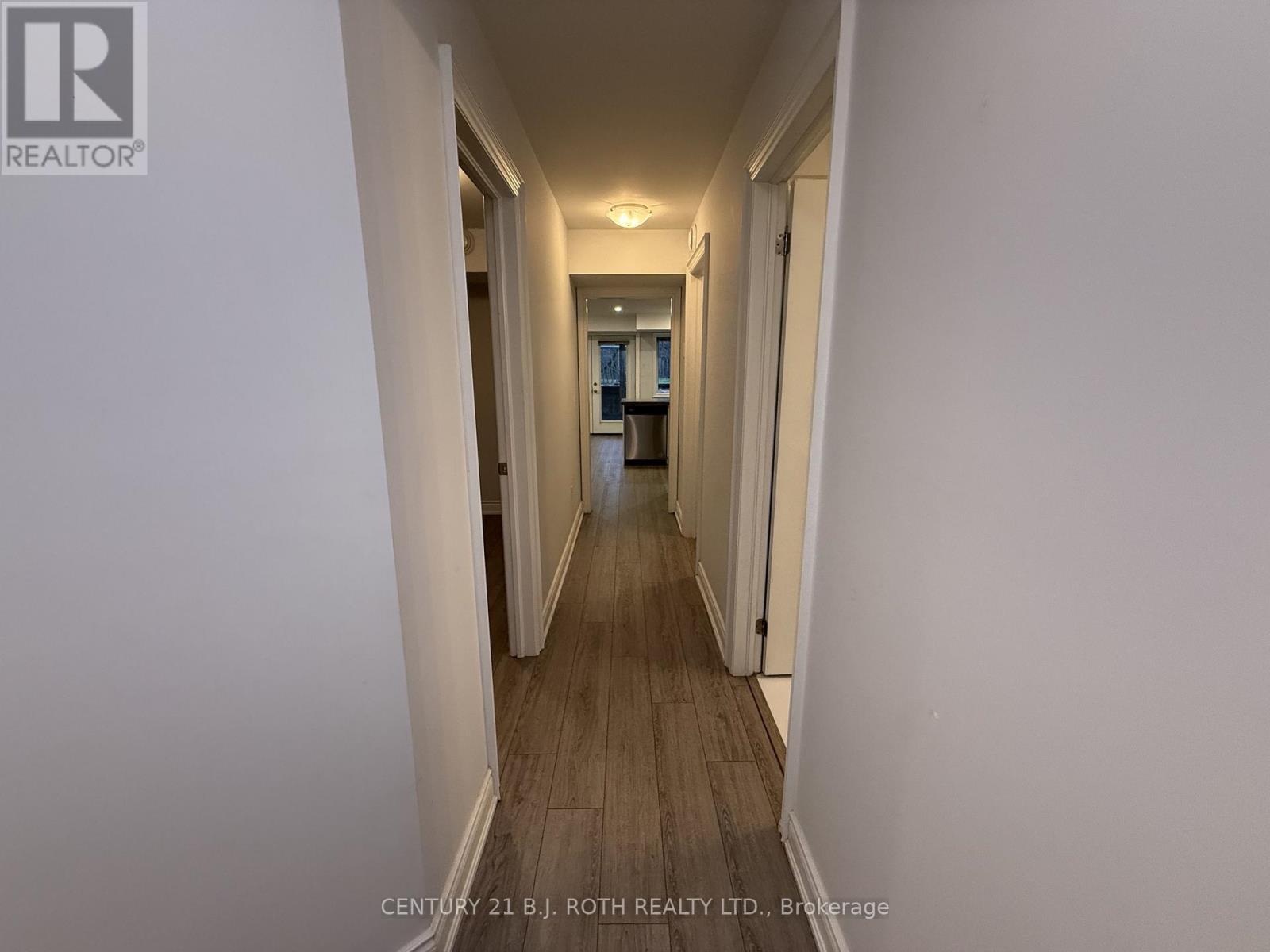 A long hallway with white walls and wood flooring.