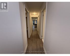 A long hallway with white walls and wood flooring.