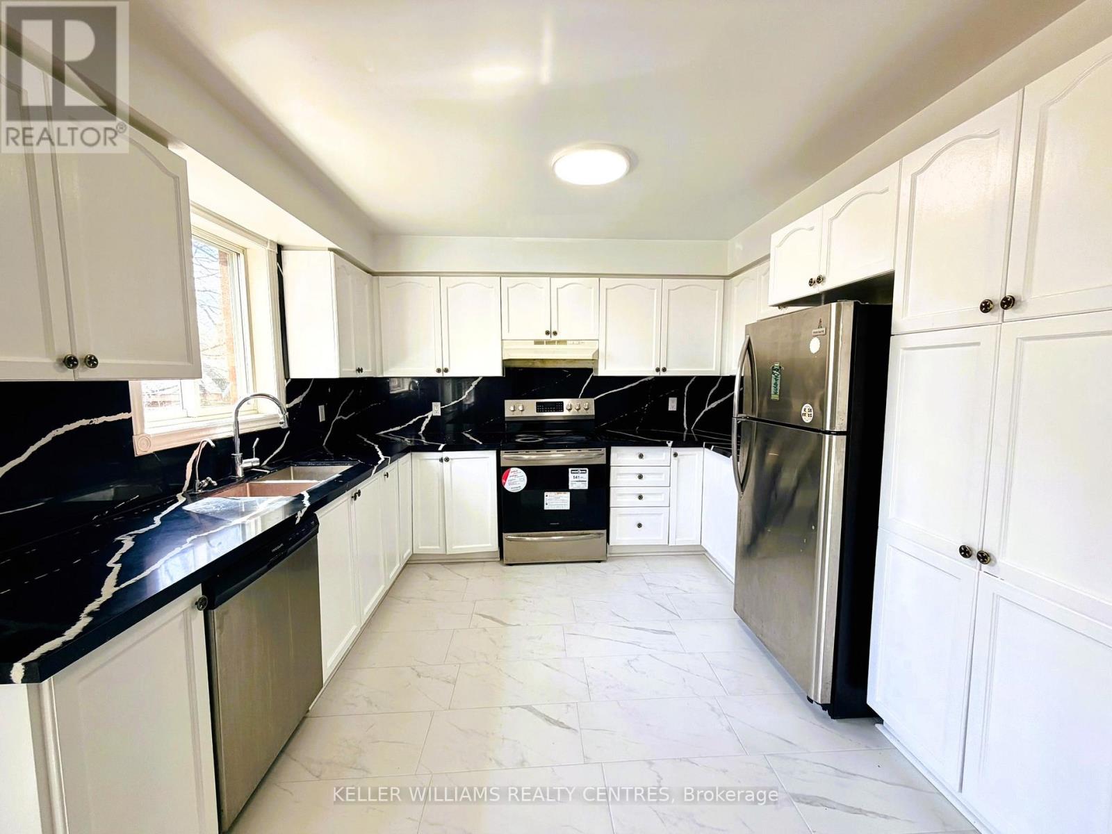 A kitchen with white cabinets and black countertops.