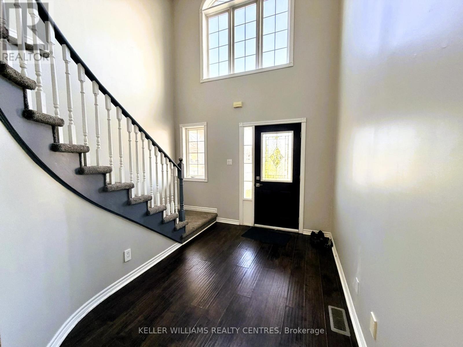 A spacious foyer with a staircase and a black door.