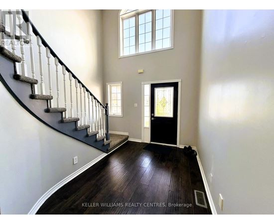 A spacious foyer with a staircase and a black door.
