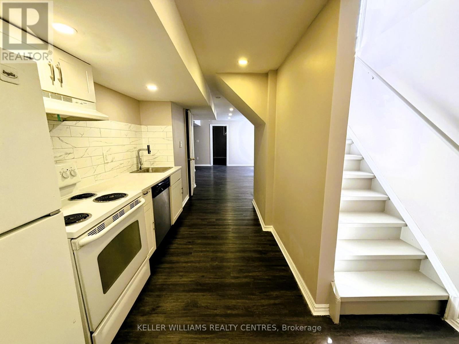 A modern kitchen with white appliances and wooden floors.