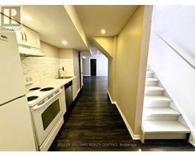 A modern kitchen with white appliances and wooden floors.