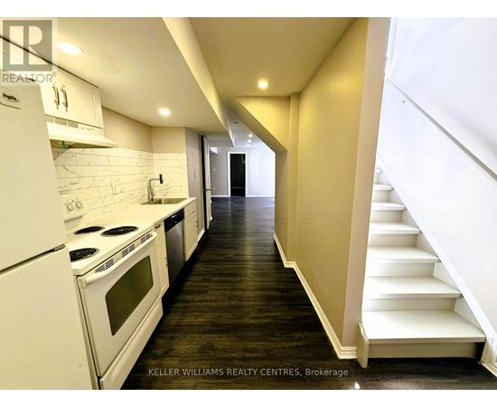 A modern kitchen with white appliances and wooden floors.