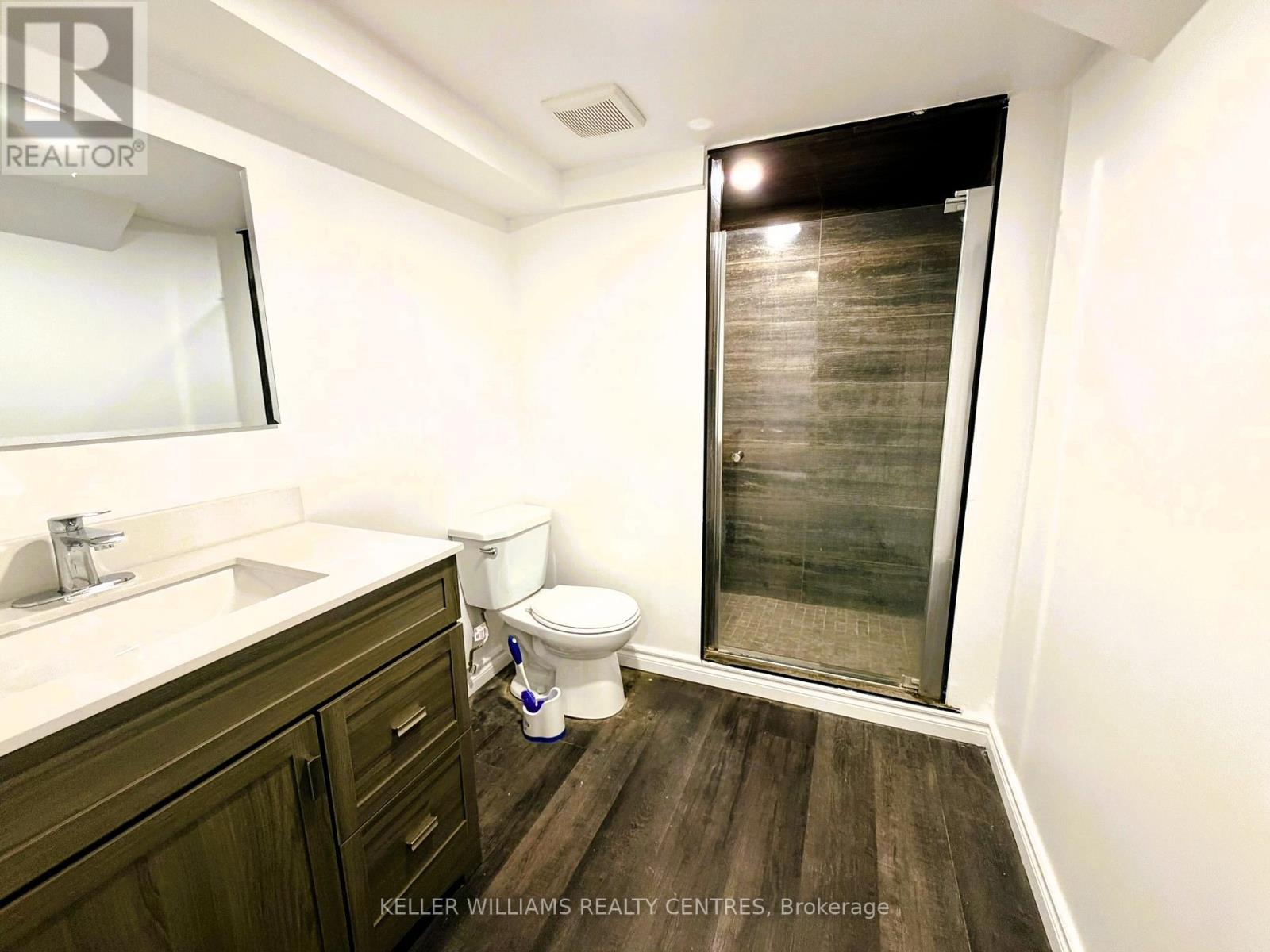 A bathroom with a toilet, sink, and a glass shower door.