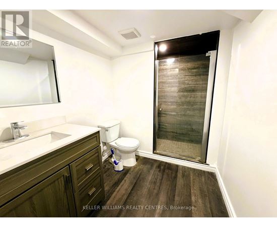 A bathroom with a toilet, sink, and a glass shower door.