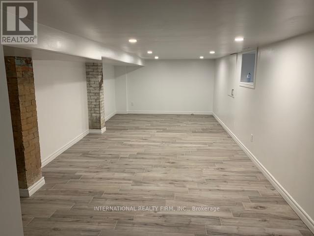 A spacious room with wooden flooring and white walls.