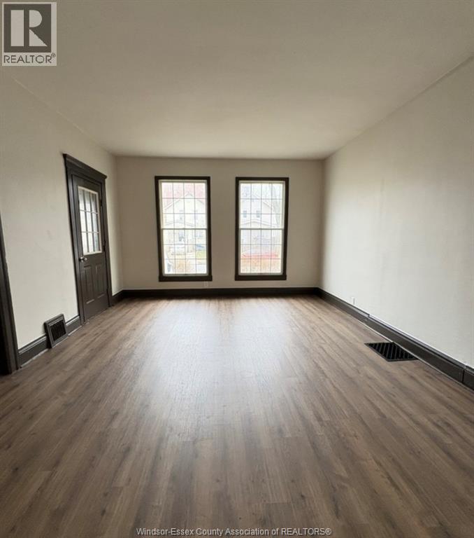 A room with wooden floors and two windows.