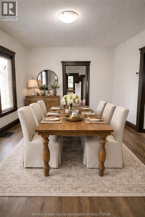 A dining room with a wooden table and white chairs.