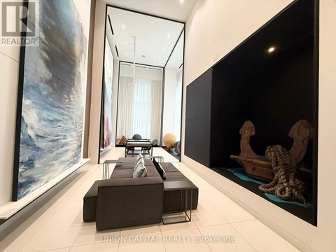 A modern living room with a large painting on the wall and a long black couch.