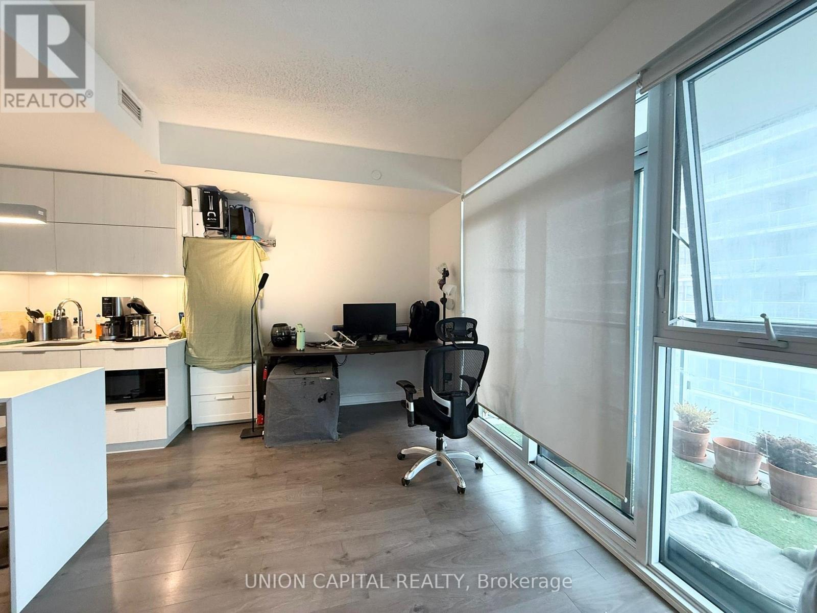 A white kitchen with a desk and chair in the middle of the room.