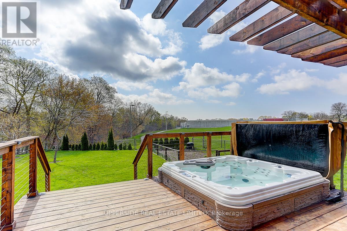 A hot tub is on a wooden deck with a view of a grassy field.