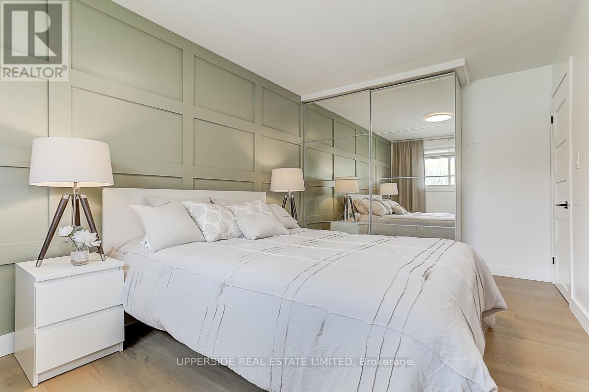 A bedroom with a large bed and a lamp on a nightstand.
