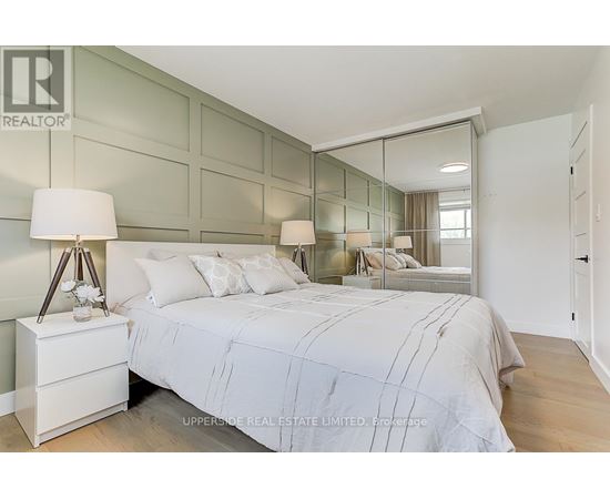 A bedroom with a large bed and a lamp on a nightstand.