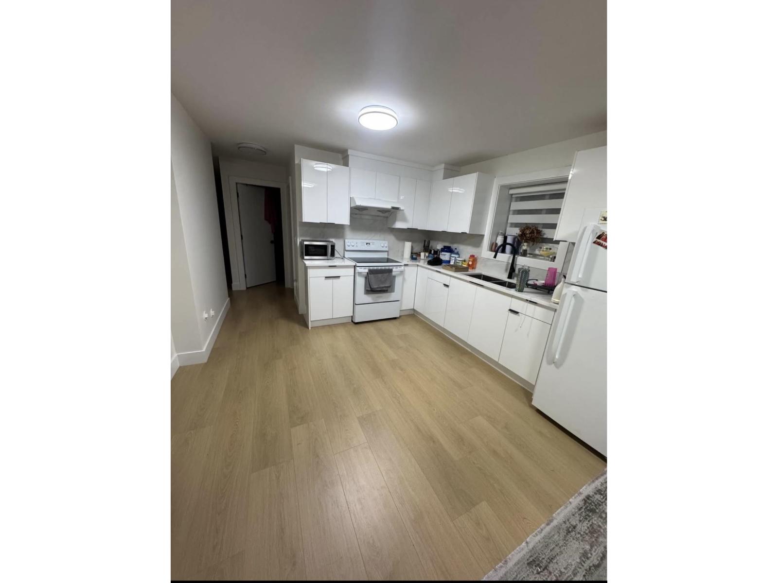 A kitchen with white appliances and wooden floors.
