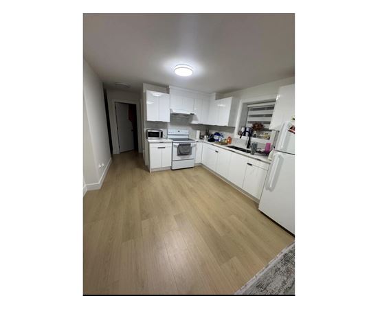 A kitchen with white appliances and wooden floors.
