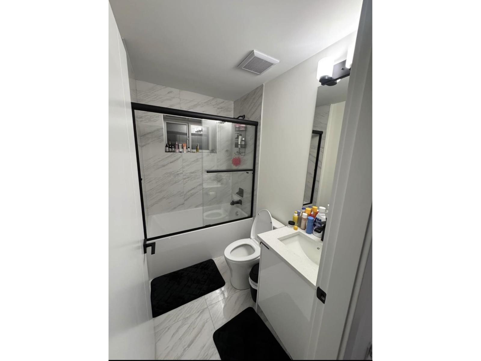 A bathroom with a toilet, sink, and mirror.