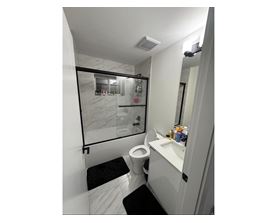 A bathroom with a toilet, sink, and mirror.