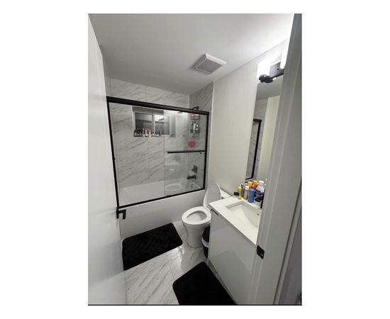 A bathroom with a toilet, sink, and mirror.