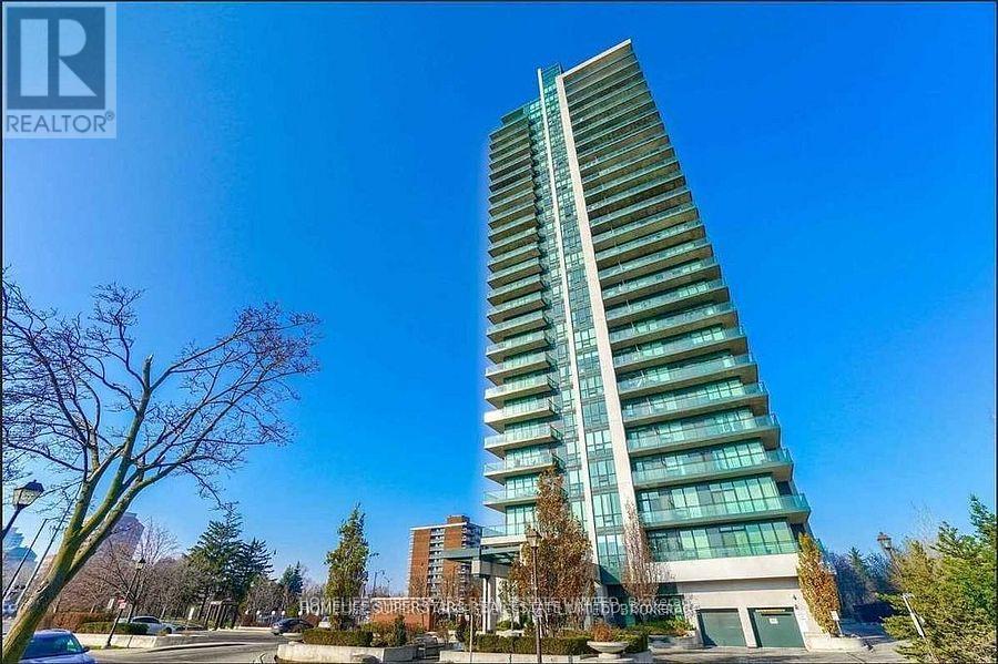 A tall building with a glass facade stands in a clear blue sky.