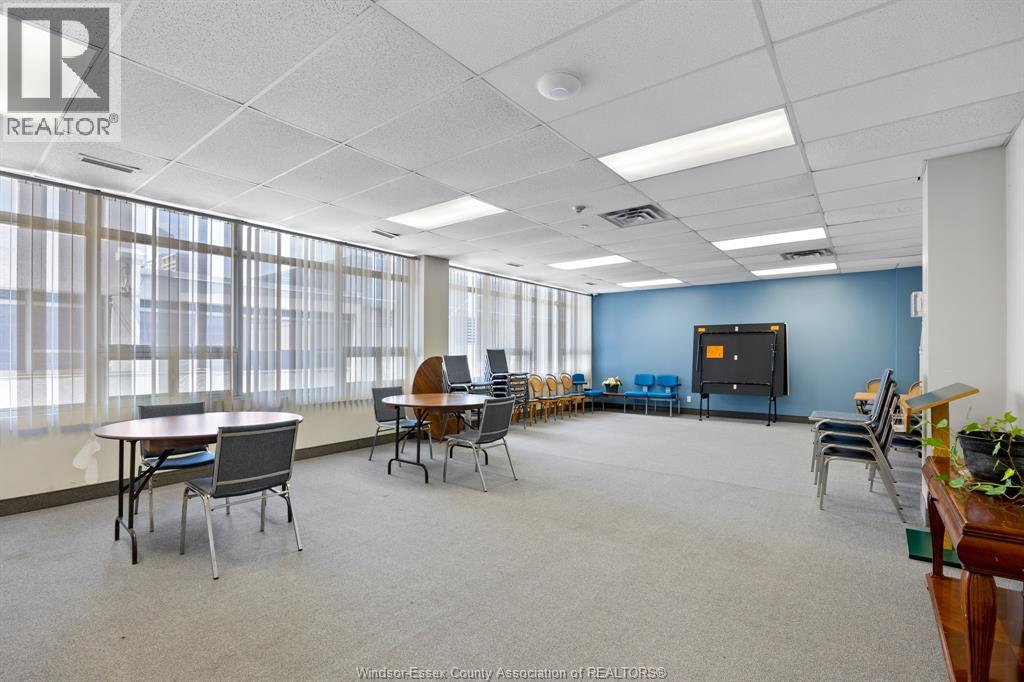 A conference room with a large table and chairs, a television, and a plant on a desk.