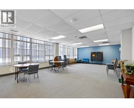A conference room with a large table and chairs, a television, and a plant on a desk.