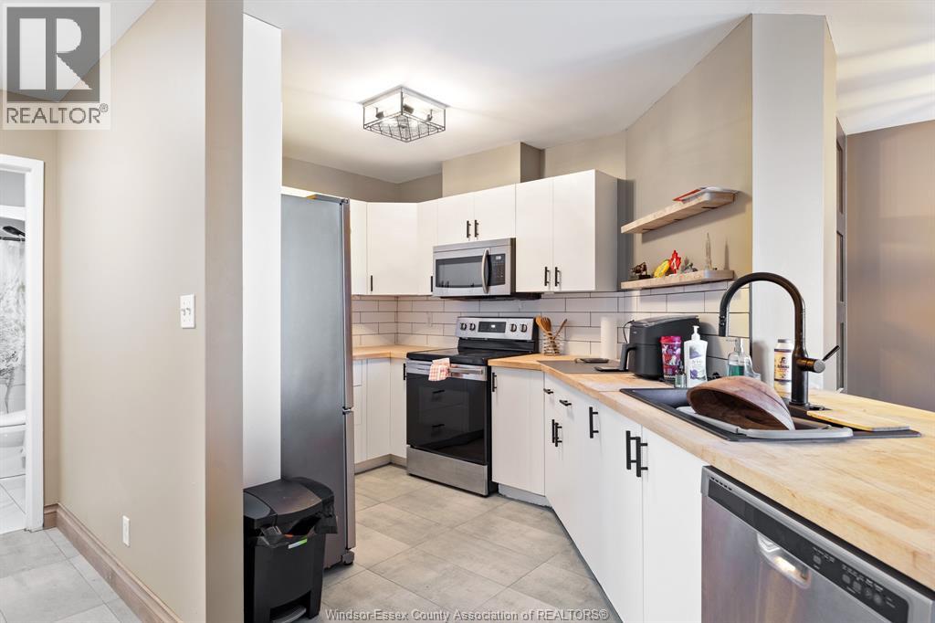 A kitchen with white cabinets and a black fridge.