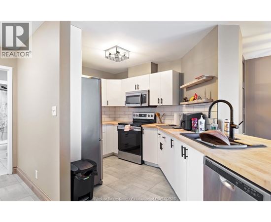 A kitchen with white cabinets and a black fridge.