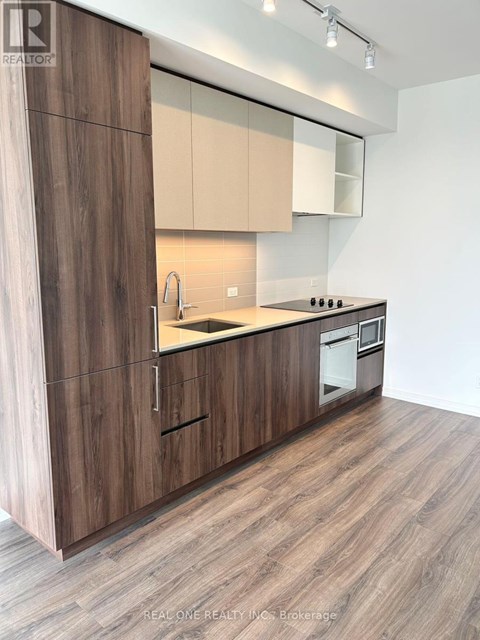 A modern kitchen with wooden cabinets and a white wall.