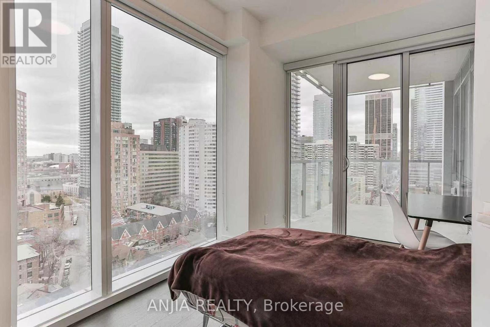 A bedroom with a large window overlooking a cityscape.