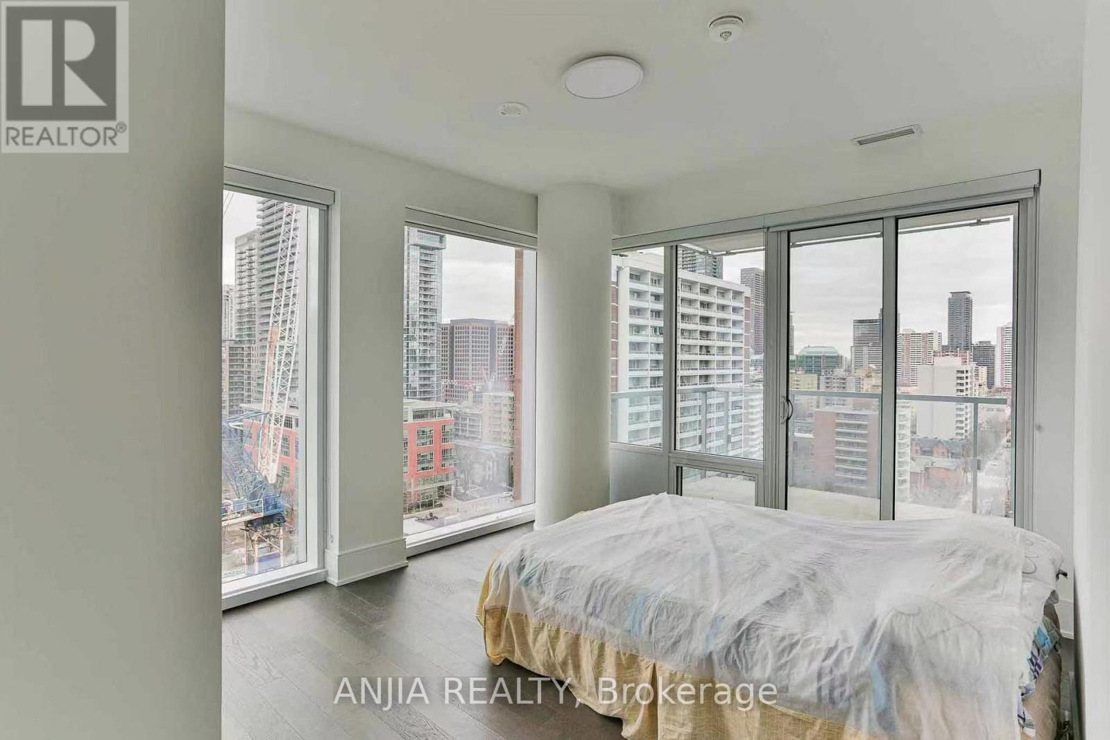 A bedroom with a large bed and a view of the city through the windows.