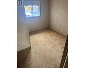 A room with a window and a carpeted floor.