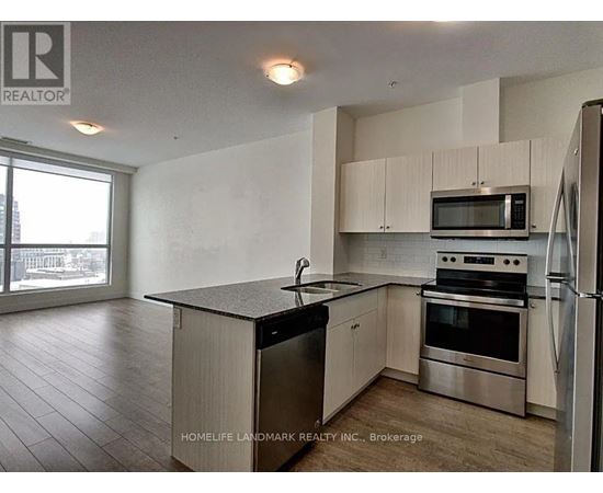A kitchen with a refrigerator, microwave, oven, and sink.