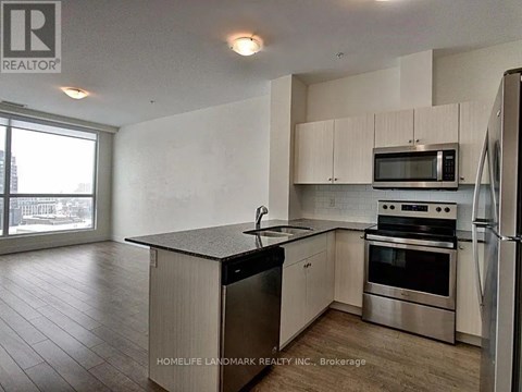 A kitchen with a refrigerator, microwave, oven, and sink.
