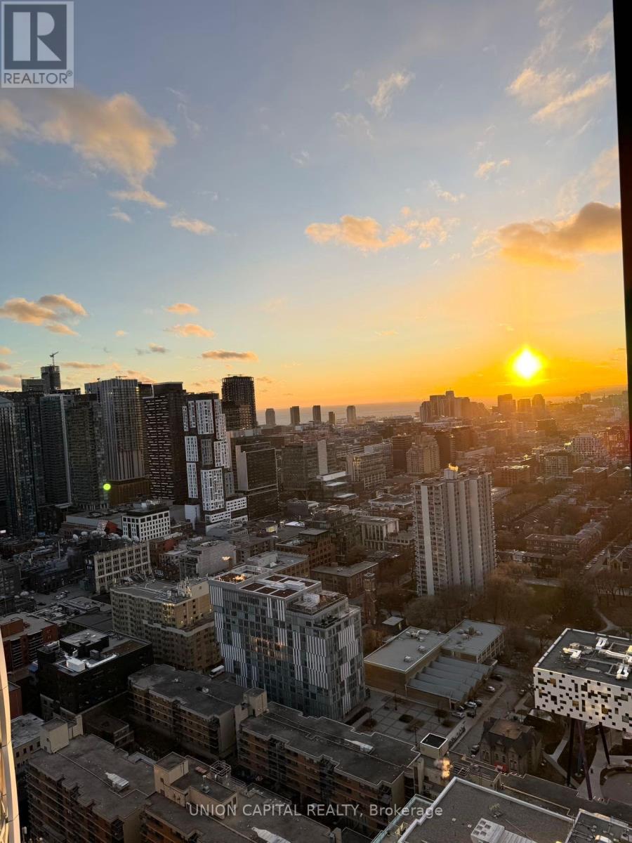 A cityscape at sunset with the sun visible in the sky.