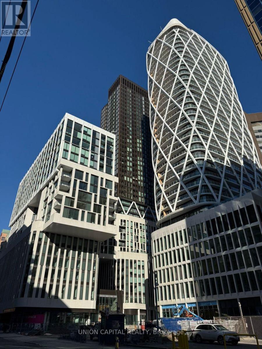A tall white building with a glass facade stands in front of a smaller building with a similar facade.