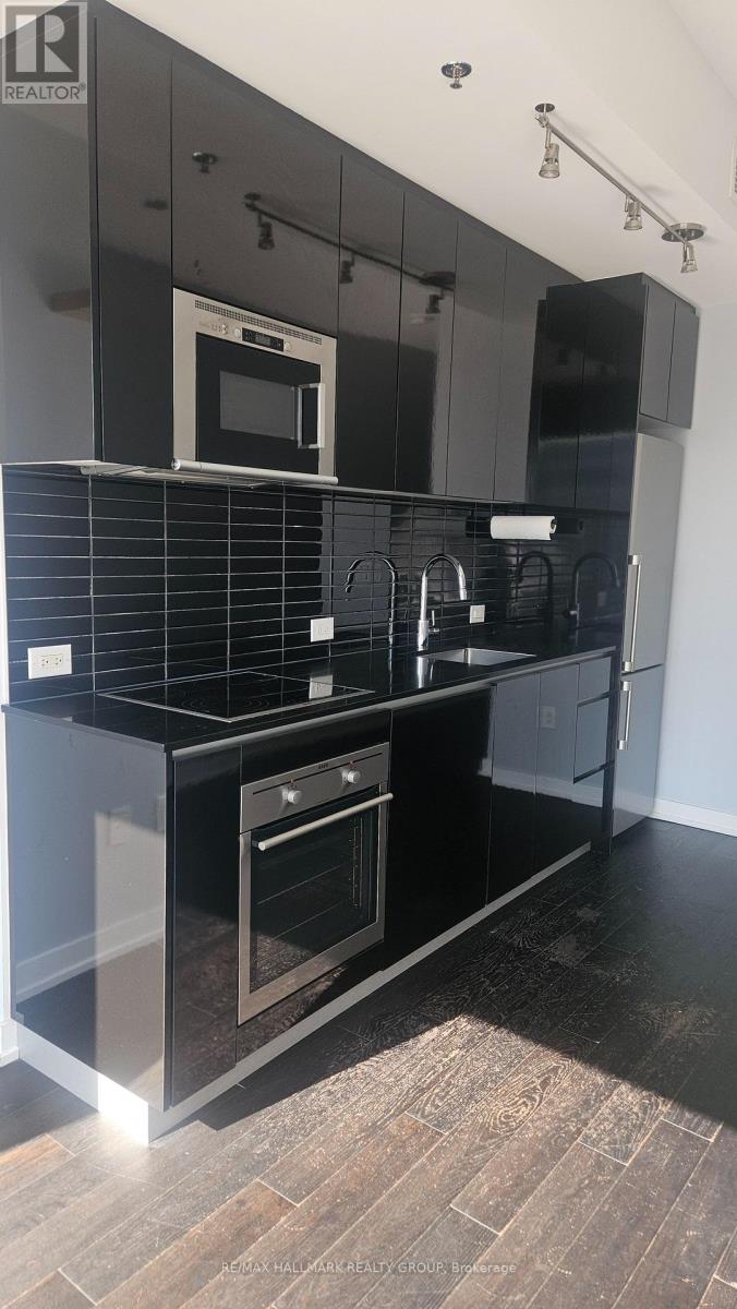 A modern kitchen with black countertops and stainless steel appliances.