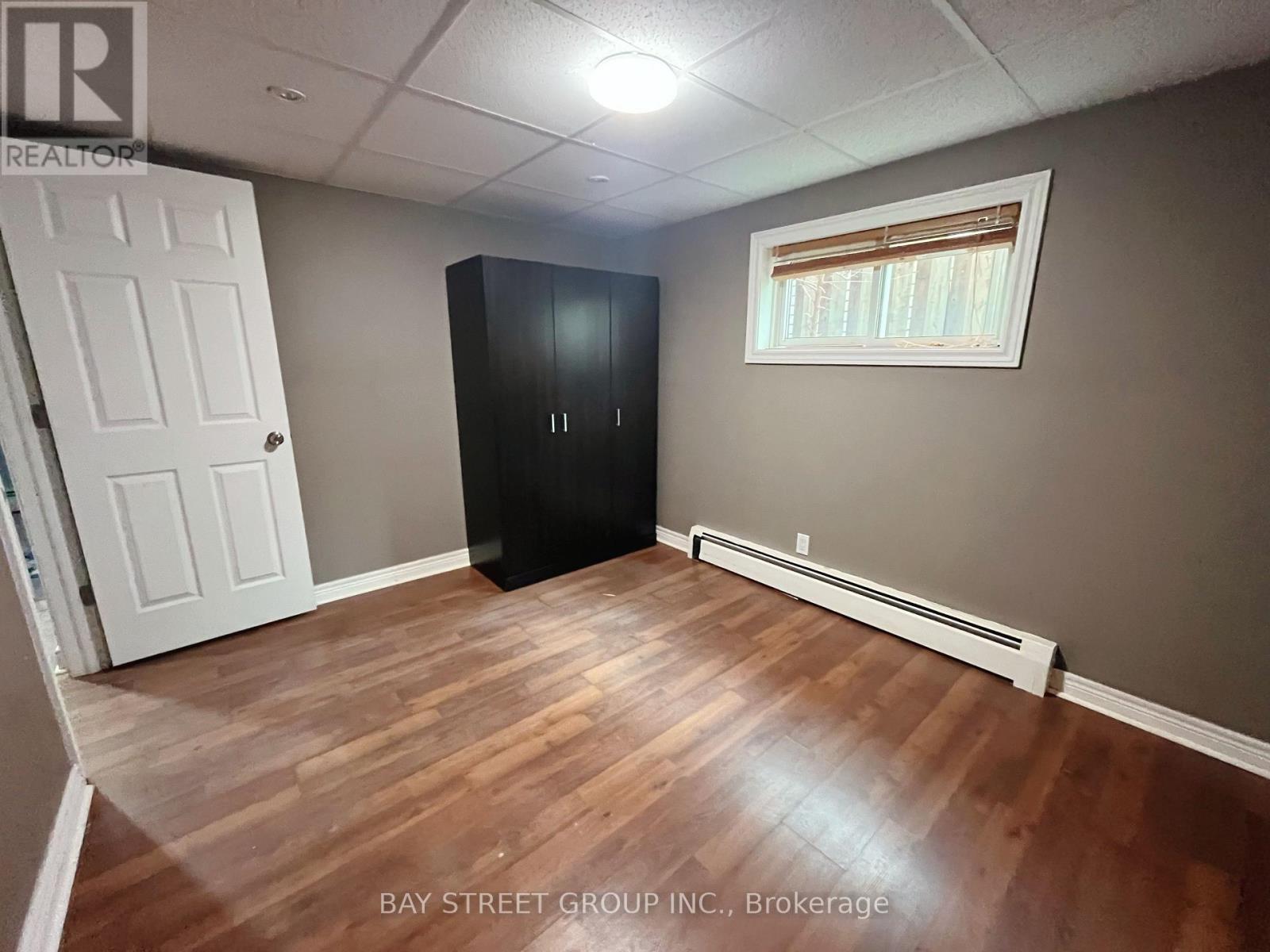 A room with a white door, a black cabinet, and a window with blinds.
