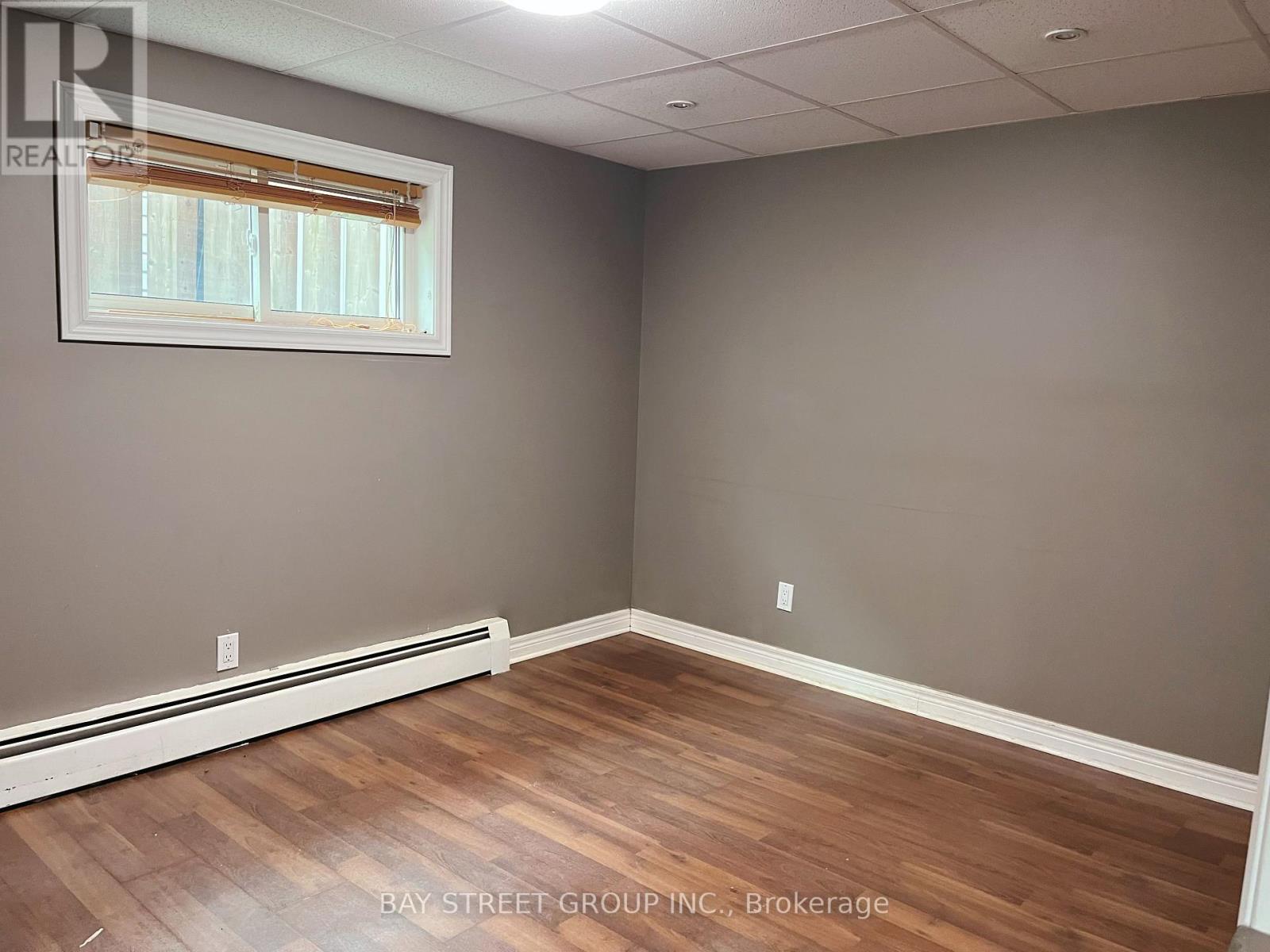 A room with wooden flooring and a window with blinds.